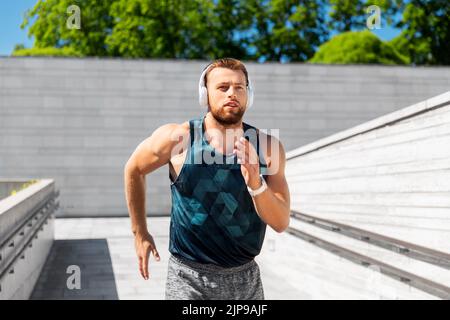 young man in headphones running outdoors Stock Photo