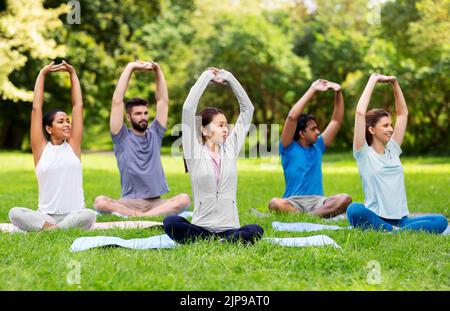 group of happy people doing yoga at summer park Stock Photo