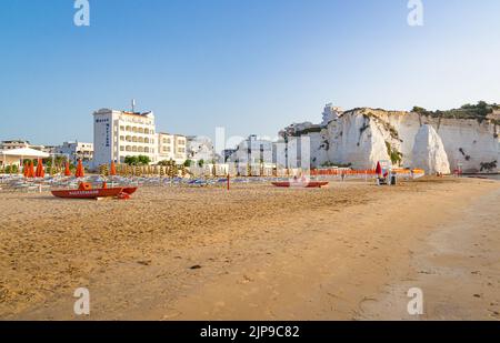 Vieste, Foggia, Italy 26 June 2021 Scialara, a sandy sunrise beach and in background on chalky rocks the oldtown of Vieste and the monolite Pizzomunno Stock Photo