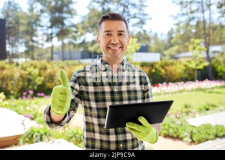 man with tablet pc showing thumbs up at garden Stock Photo