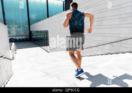 young man in headphones running downstairs Stock Photo