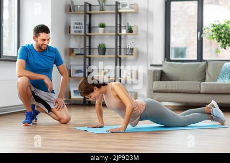 woman with personal trainer doing push-ups at home Stock Photo