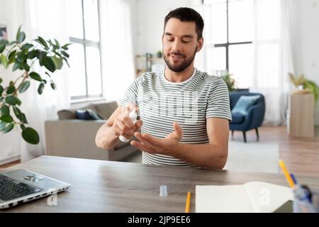 man using hand sanitizer at home office Stock Photo