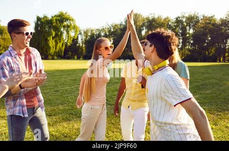 Happy young men and woman on meeting with friends are going to have good time at summer park party Stock Photo