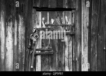 An old gas mask and a dangerous sign with a painted skull hang on the door, gas attack in Ukraine during the war, protective mask, ecology, chemical a Stock Photo