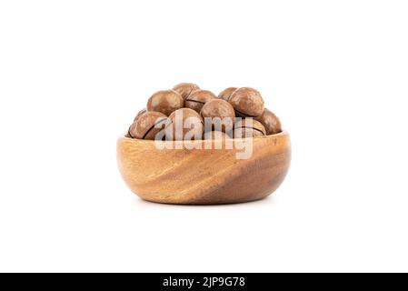 Wooden bowl full of macadamia nuts on a white background. Copy space. Stock Photo