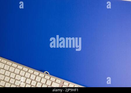 A top close-up view of the edge of a white keyboard against a blue background Stock Photo