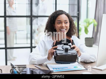 Girl in VR glasses of virtual reality with gamepad playing game Stock Photo