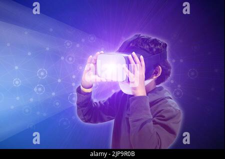 Asian kid boy using metaverse VR virtual reality glasses to digital technology game. Stock Photo