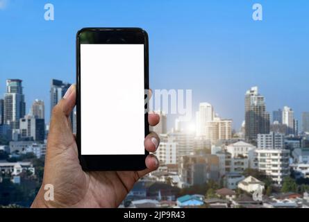 Asian man using hand hold black smartphone on blured city background, Smartphone mockup. Stock Photo