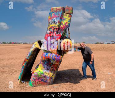 Cadillac Ranch, Amarillo, Texas. Several older Cadillacs buried nose down in a field.  Cars are painted with several colors of spray paint by tourists. Stock Photo