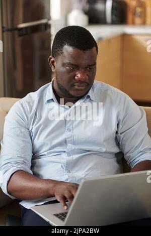 Serious Black software developer coding on laptop at home Stock Photo