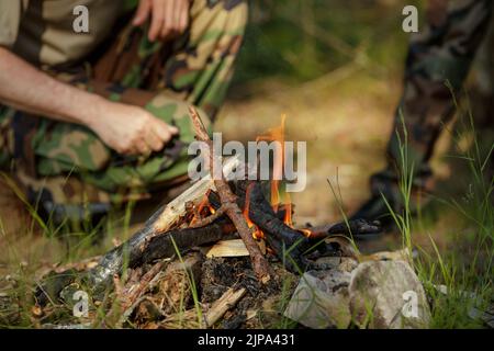 Man is making campfire in the woods. The concept of adventure, travel, tourism, camping, survival and evacuation. Stock Photo