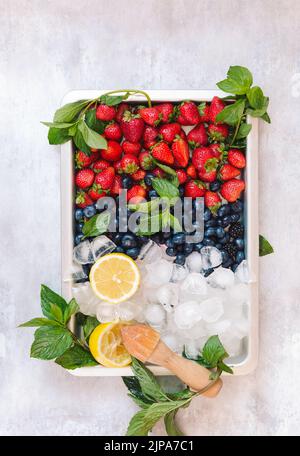 Berry plate. Berry fruits and lemons in a tray of ice cubes. Stock Photo