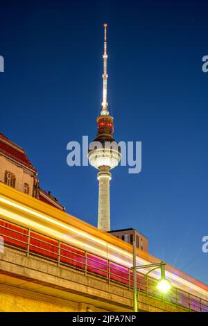 The famous Television Tower in Berlin at night with a motion blurred commuter train Stock Photo