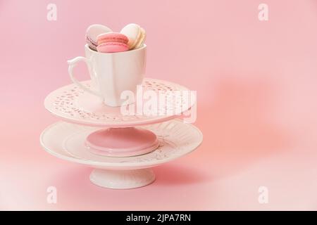 Cake stands in various colors and  cup of macaroons on top. Copy space, selective focus Stock Photo