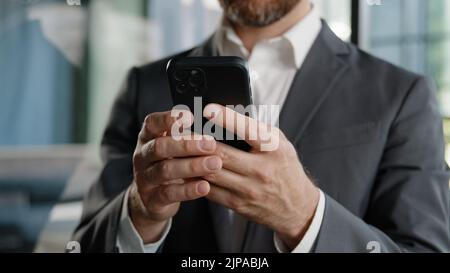 Closeup male hands unrecognizable unknown Caucasian man professional worker businessman holding cellphone mobile phone texting typing chatting in Stock Photo