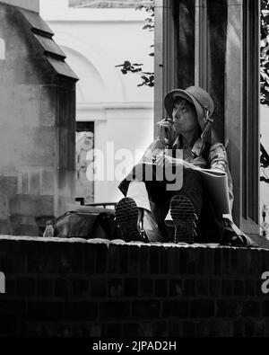 an artist lady sitting in the ruins of an ancient church (St Dunstan in the East Church Garden) in London, United Kingdom. Stock Photo