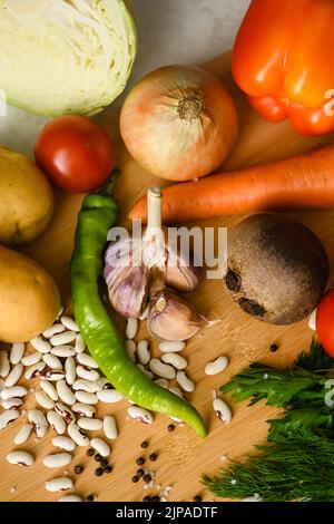 Ingredients for cooking the national Ukrainian dish - borscht. Fresh vegetables are arranged on a wooden cutting board. Preparing to cook borscht. Stock Photo