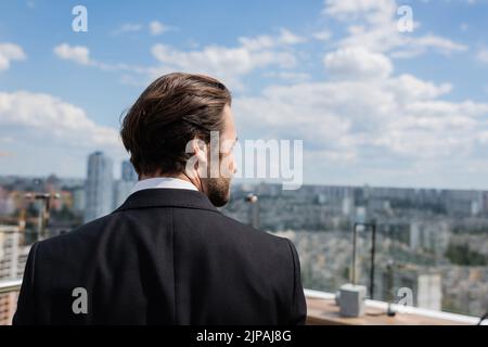 Side view of brunette groom looking away on terrace Stock Photo