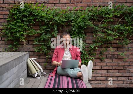 Focused young businessman freelancer engaged in distant work from street make report on laptop Stock Photo