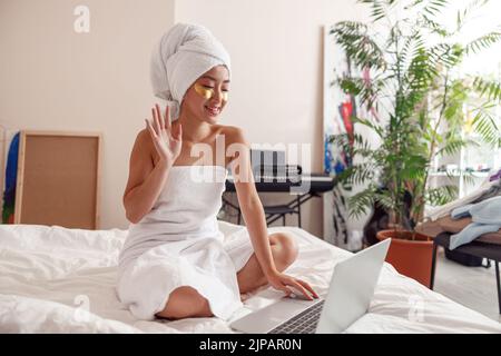 Joyful Asian woman using notebook after shower at home Stock Photo