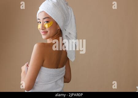 Smiling woman with golden patches under eyes standing in studio Stock Photo