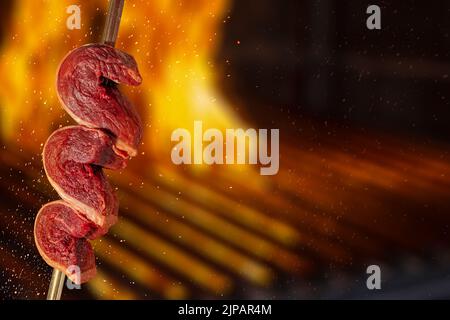 raw picanha on skewer, traditional brazilian beef cut on fire background Stock Photo