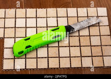 construction knife with replaceable blades lying on a ceramic tile Stock Photo
