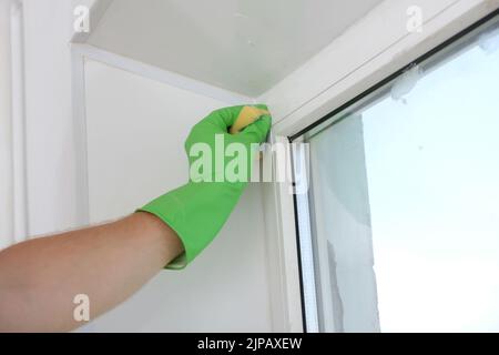 A man washes a glass window and a plastic frame with a folk remedy with household soap. Ecology. Stock Photo