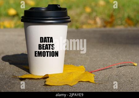 On a yellow maple leaf there is a cup of coffee on which is written - data beats emotion. Technology concept Stock Photo