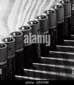 A closeup of batteries all in a line casting a shadow Stock Photo