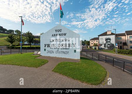 Sign entering Free Derry with mural by Bogside Artists on side of house in Derry, Northern Ireland. Stock Photo