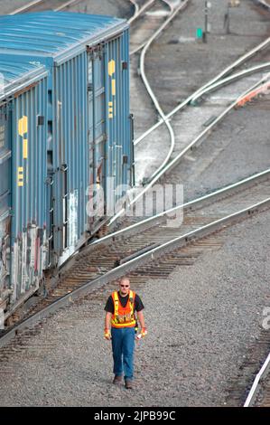 Railroad train yard with sidings and switchers and engines and cars and repair facilities in Utah Saftey vest colors Stock Photo