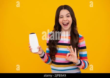 Amazed teenager. Teenage girl with shampoos conditioners or shower gel. Kids hair care cosmetic product, shampoo bottle. Excited teen girl. Stock Photo