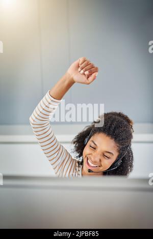Another deal done. a young woman doing a fist pump while working on a computer at home. Stock Photo