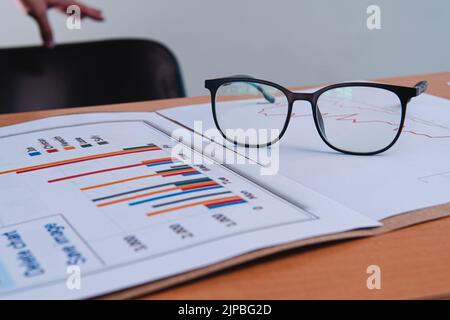 Work table of a businessman with papers, graphs and glasses. Business presentation template with papers, folder and a chair in the background. High quality photo Stock Photo