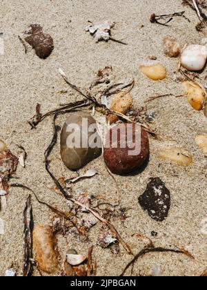Sea stones on sandy wet beach. Summer background texture wallpaper. Top aerial view above sunny beach day. various beautiful multi-colored round Stock Photo