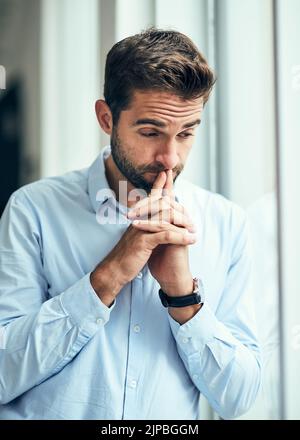 Am I making the right decision. a handsome young businessman looking worried in an office. Stock Photo