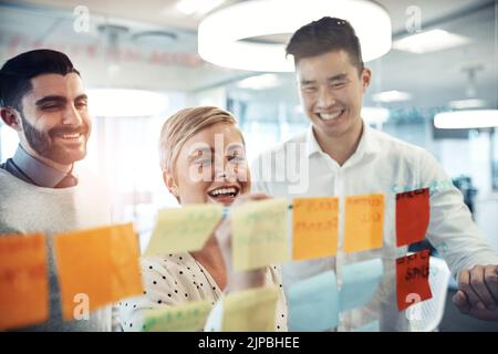 Now this is a great idea. businesspeople brainstorming with sticky notes on a glass wall in the office. Stock Photo