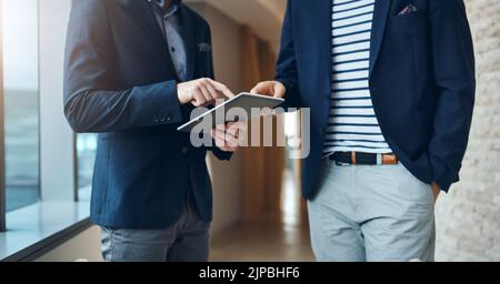 Using technology to smart moves. two businessmen using a digital tablet together in a modern office. Stock Photo