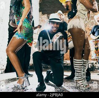 Dancing is pure happiness. a man playing music while samba dancers perform in a carnival. Stock Photo