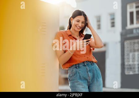 Woman texting, browsing and scrolling on phone while chatting on social media, waiting for taxi and commuting in an urban city. Happy, trendy and Stock Photo
