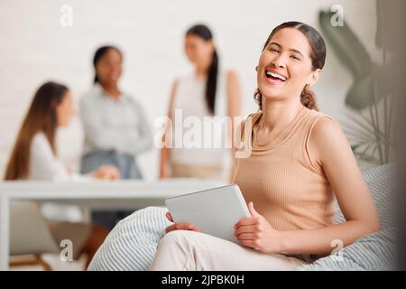 Businesswoman, team leader or manager on a tablet working at a female only company or women empowerment workplace with colleagues in background Stock Photo