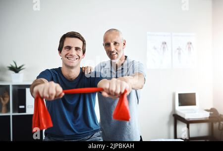 Feels great to be fully mobile again. Portrait of a physiotherapist helping a patient stretch with resistance bands. Stock Photo