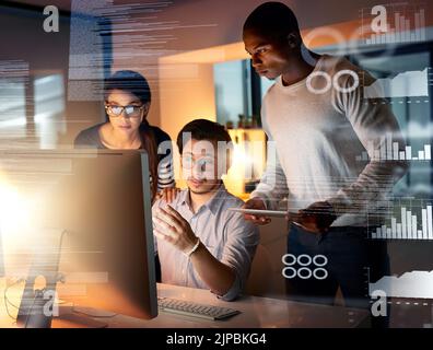 Theyre always working on the next big thing. colleagues connecting to a user interface while working in an office at night. Stock Photo
