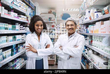We are here to help. Cropped portrait of two pharmacists standing together with their arms crossed in a pharmacy. Stock Photo
