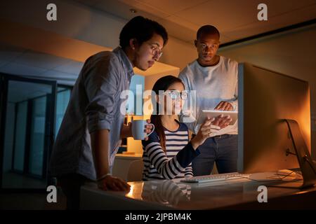 Working together to reach deadlines. computer programmers working together late in the office. Stock Photo