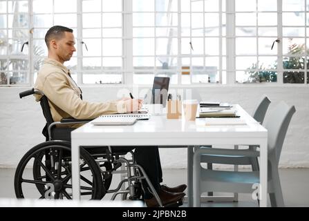 Wheelchair, disabled and handicap business man working, planning and writing ideas in an inclusive, accessible and independent office workplace Stock Photo