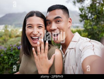 Engagement, ring and celebration with a young couple announcing their happy news and special occasion. Closeup portrait of a man and woman taking a Stock Photo